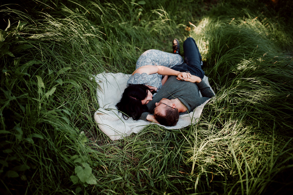 engaged couple lying in the grass at Winnipeg Park