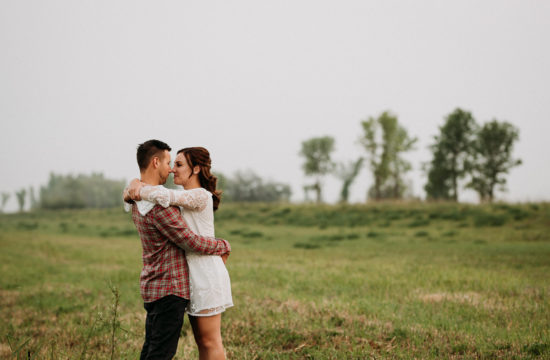 engaged winnipeg couple embracing in a field