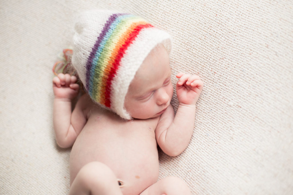 newborn baby girl in rainbow bonnet