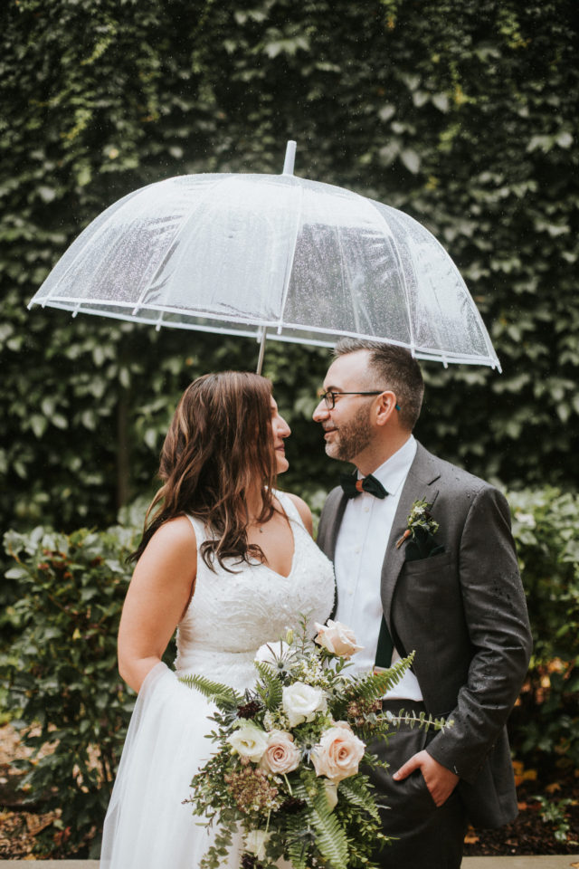 Bride and groom underneath umbrella in Winnipeg's Exchange District